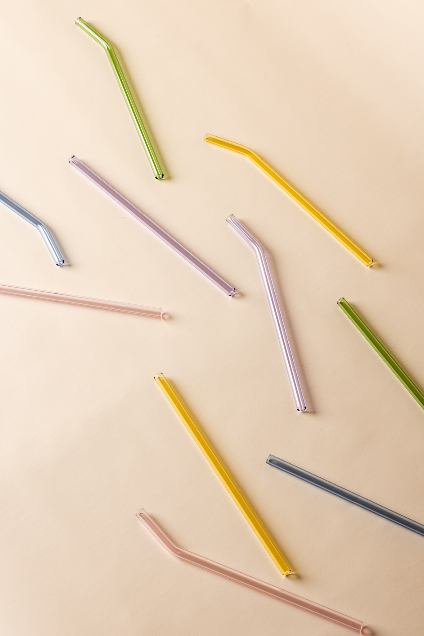 Classic glass straws on a table, including bent glass straws and straight glass straws in multiple colors